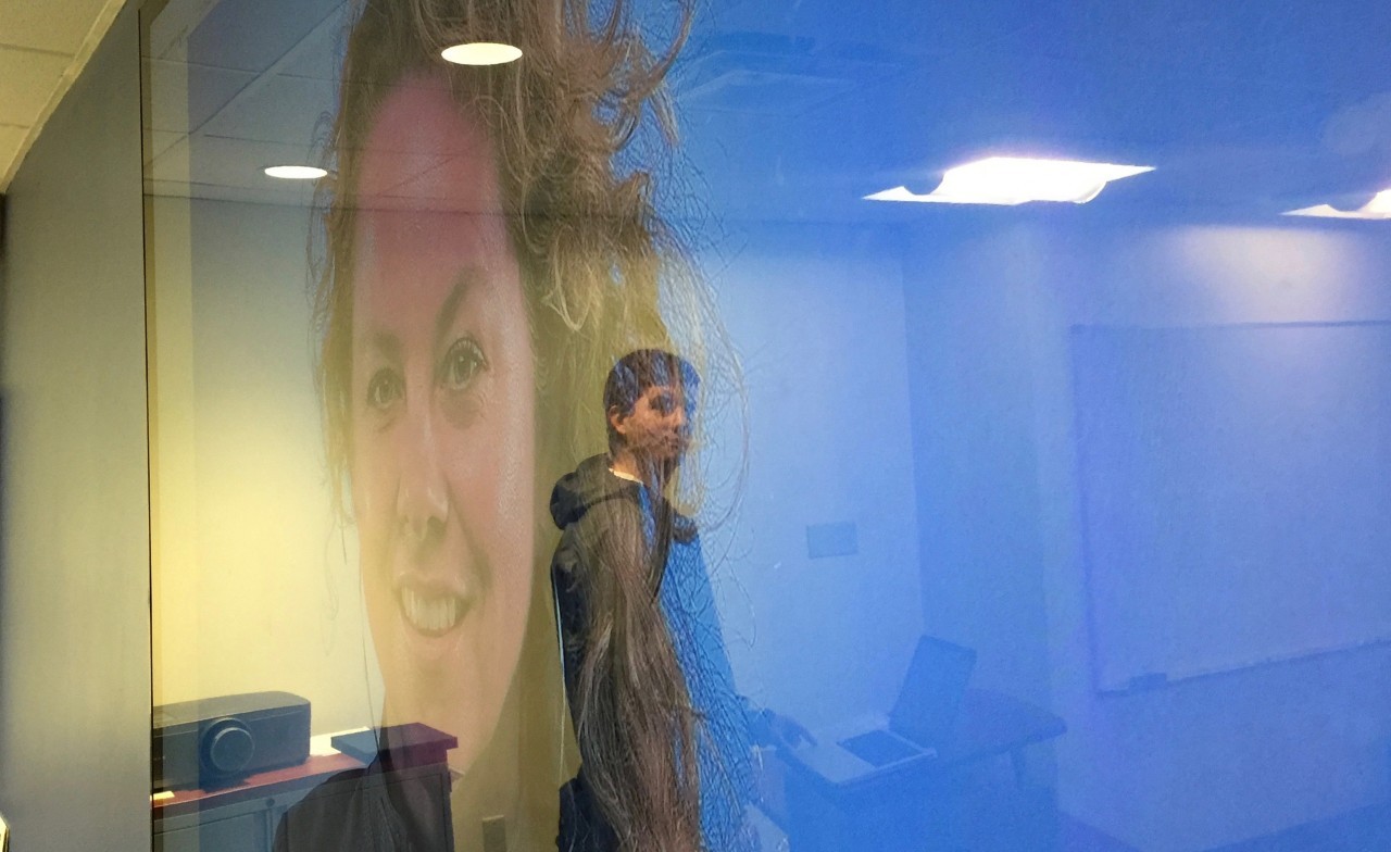 Reflection of student in the screen showing a portrait of photographer Barbara Davidson